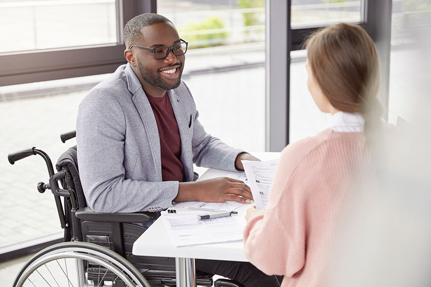 En man i rullstol och en kvinna samtalar under ett möte