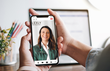 Hemskärmen på en mobiltelefon visar Lexlys hemsida med en leende kvinna