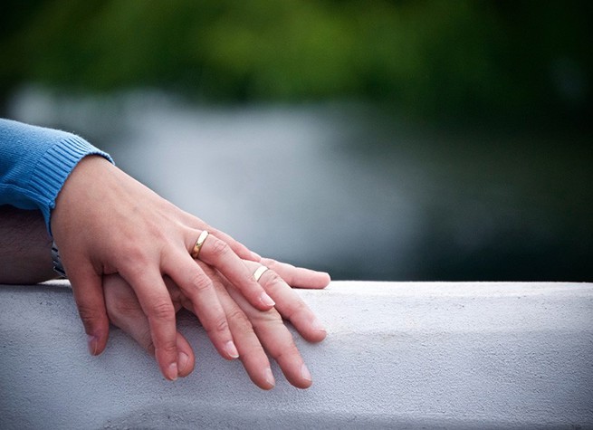 Två personer med varsin vigselring håller hand